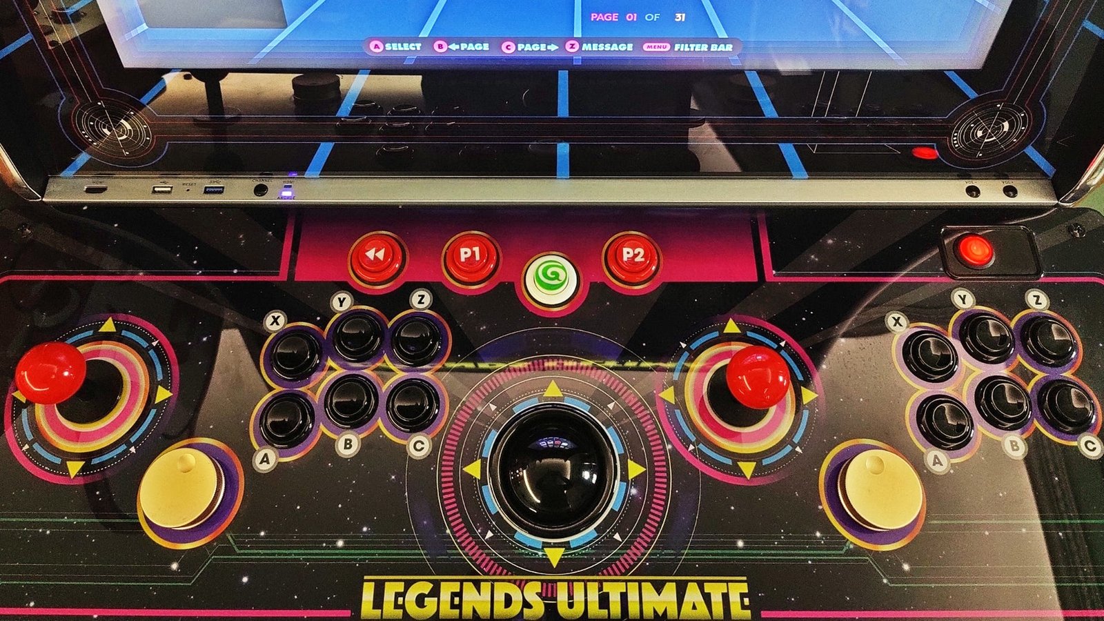 المنظر العلوي للوحة تحكم Legends Ultimate ، والتي تشتمل على ذراعان تحكم ، و 12 زرًا ، واثنين من أزرار التحكم وكرة التتبع.