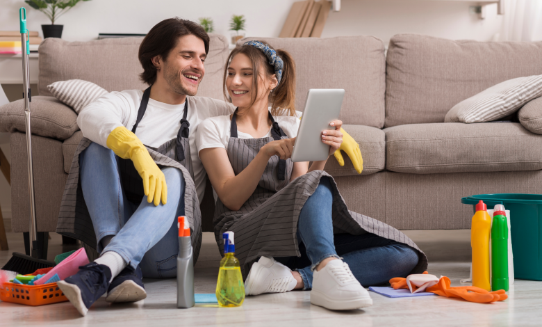 Cheerful young couple pausing from cleaning to use an app on a tablet