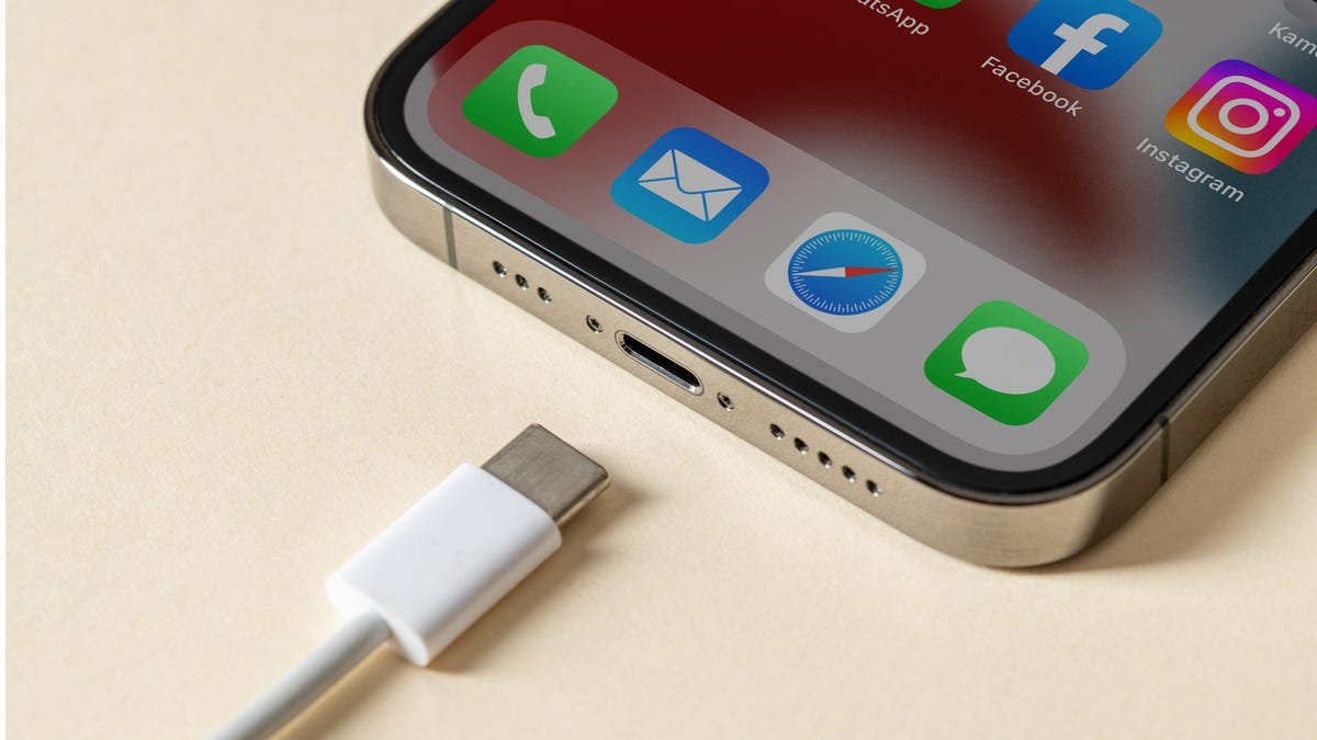مع وجود iPhone على الطاولة ، يتم محاذاة كابل شحن USB-C مع منفذ الشحن.